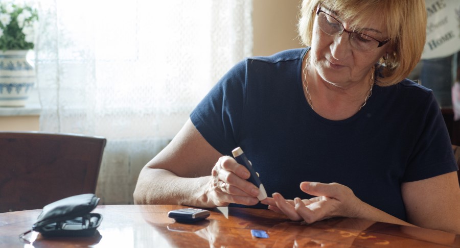 Senior woman checking blood sugar level with test at home