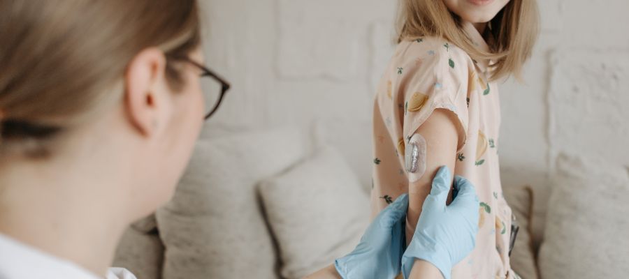 A girl has a glucose monitor fitted by a healthcare professional 